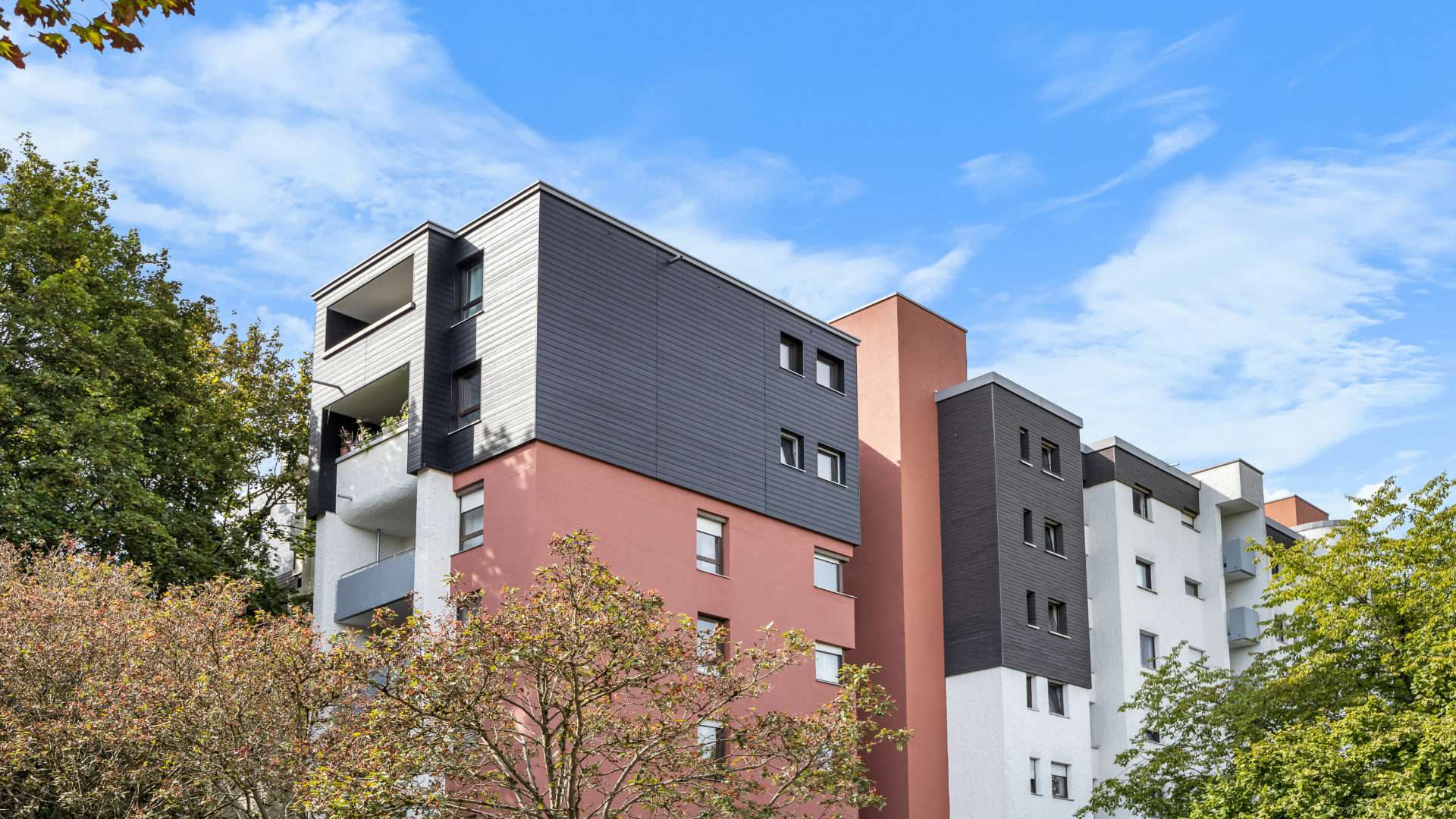 Mehrfamilienhaus in rot, weiß und mit Holz